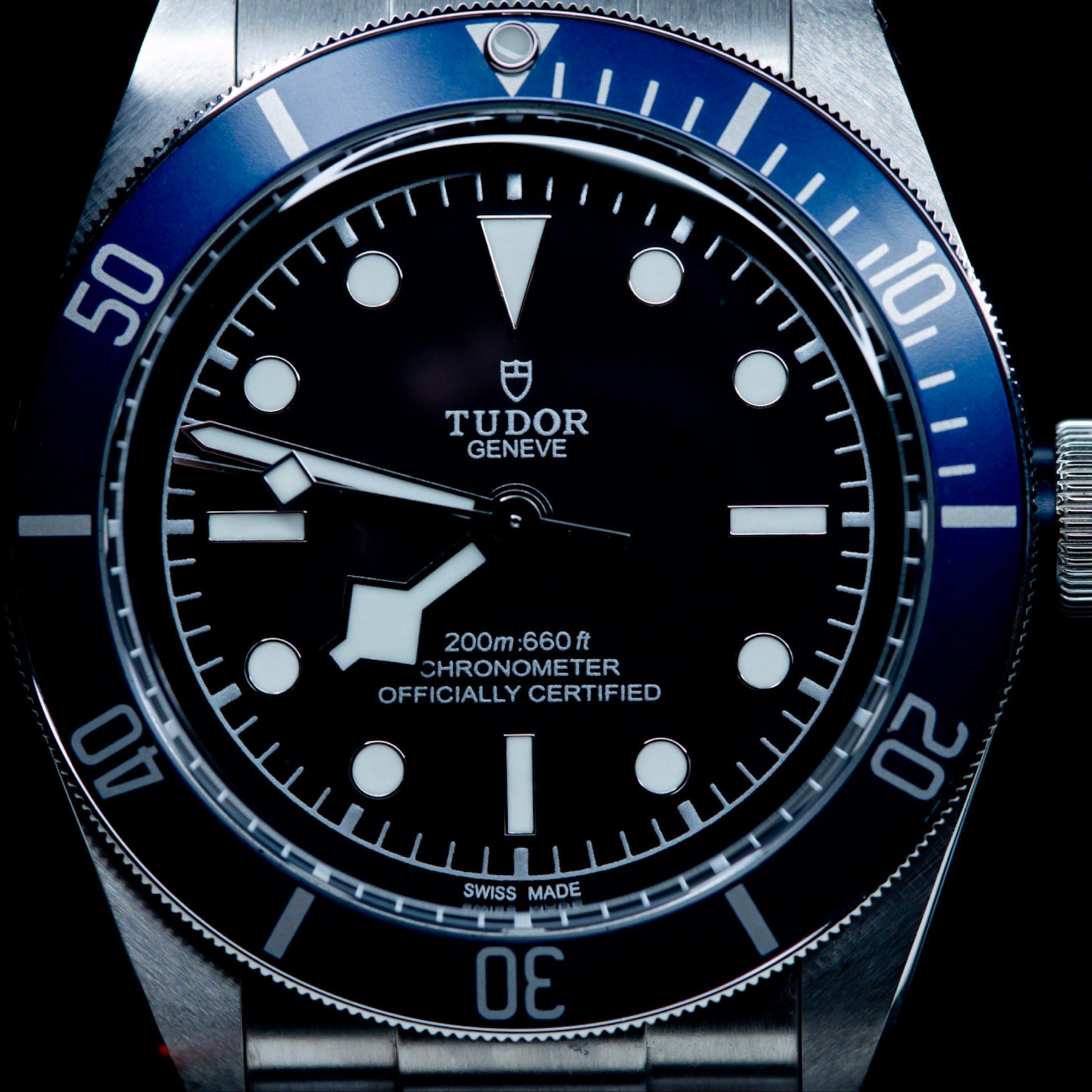Close-up of Tudor Black Bay Heritage 79230B watch dial with blue bezel and black face, showcasing its chronometer certification.