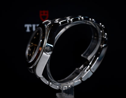 Tudor Black Bay 58 GMT Coke watch showcased from the side, highlighting the black dial and steel bracelet.