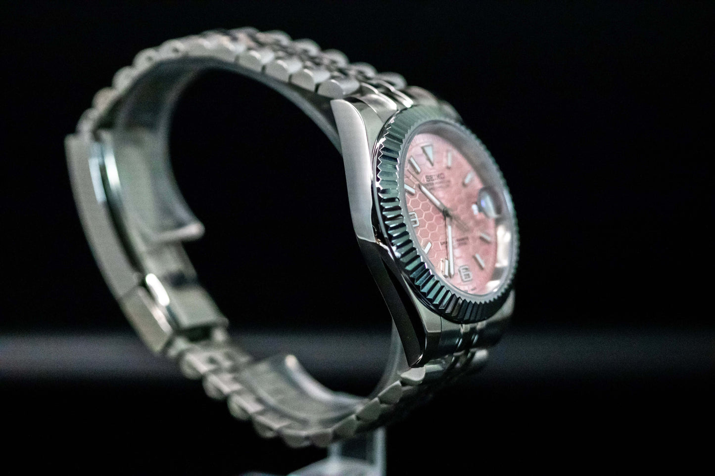 Seiko Mod Pink Land Dweller watch with salmon dial and stainless steel bracelet, showcasing elegant design and durability.