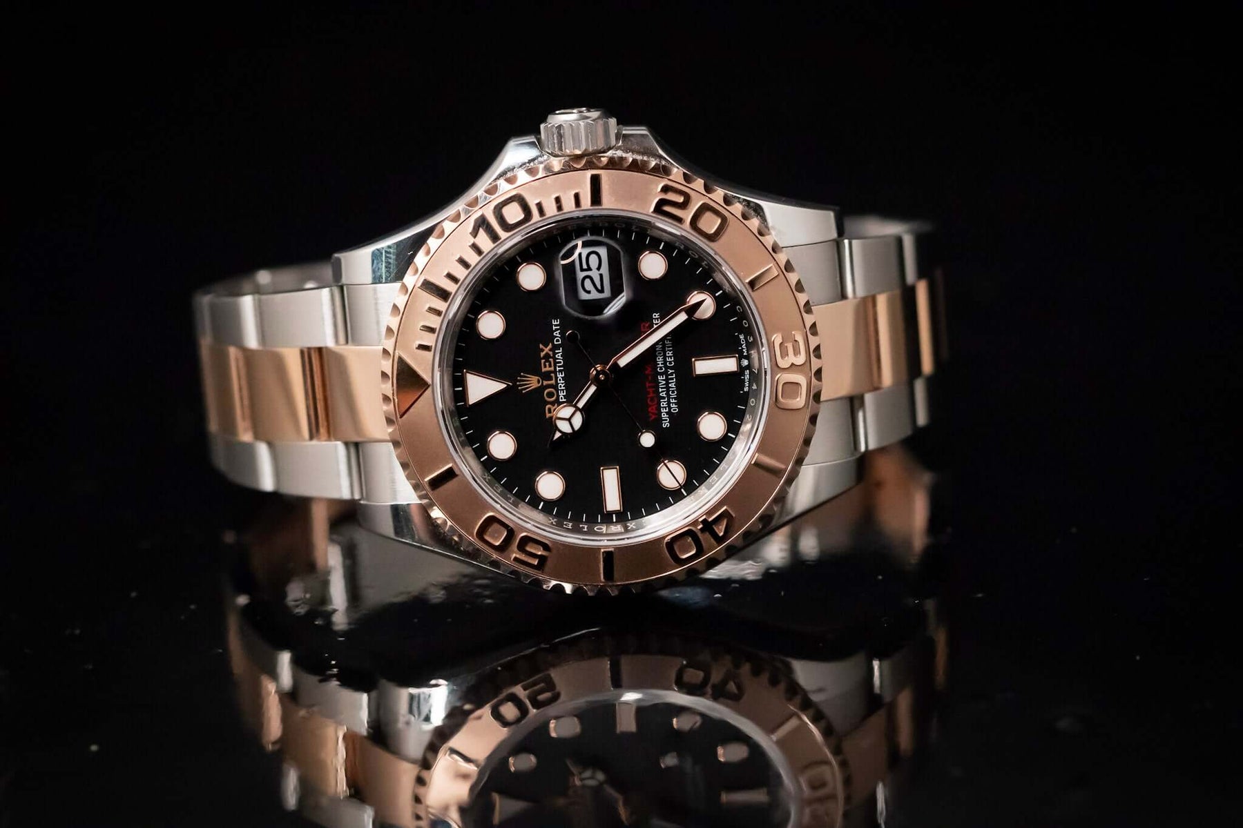 2023 Rolex Yacht-Master 40 watch on a reflective surface showcasing Everose gold and black dial