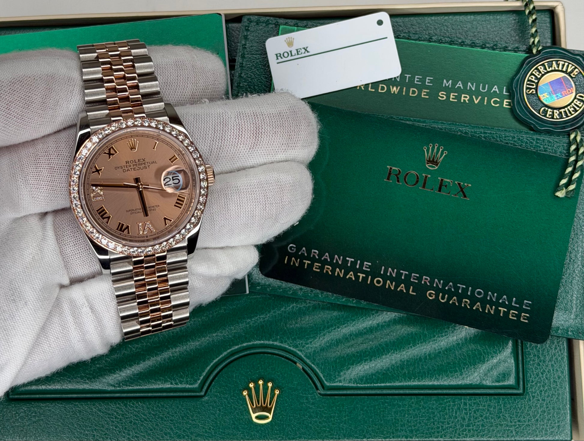 Rolex Datejust 36 watch displayed on a hand with certificate and green packaging.