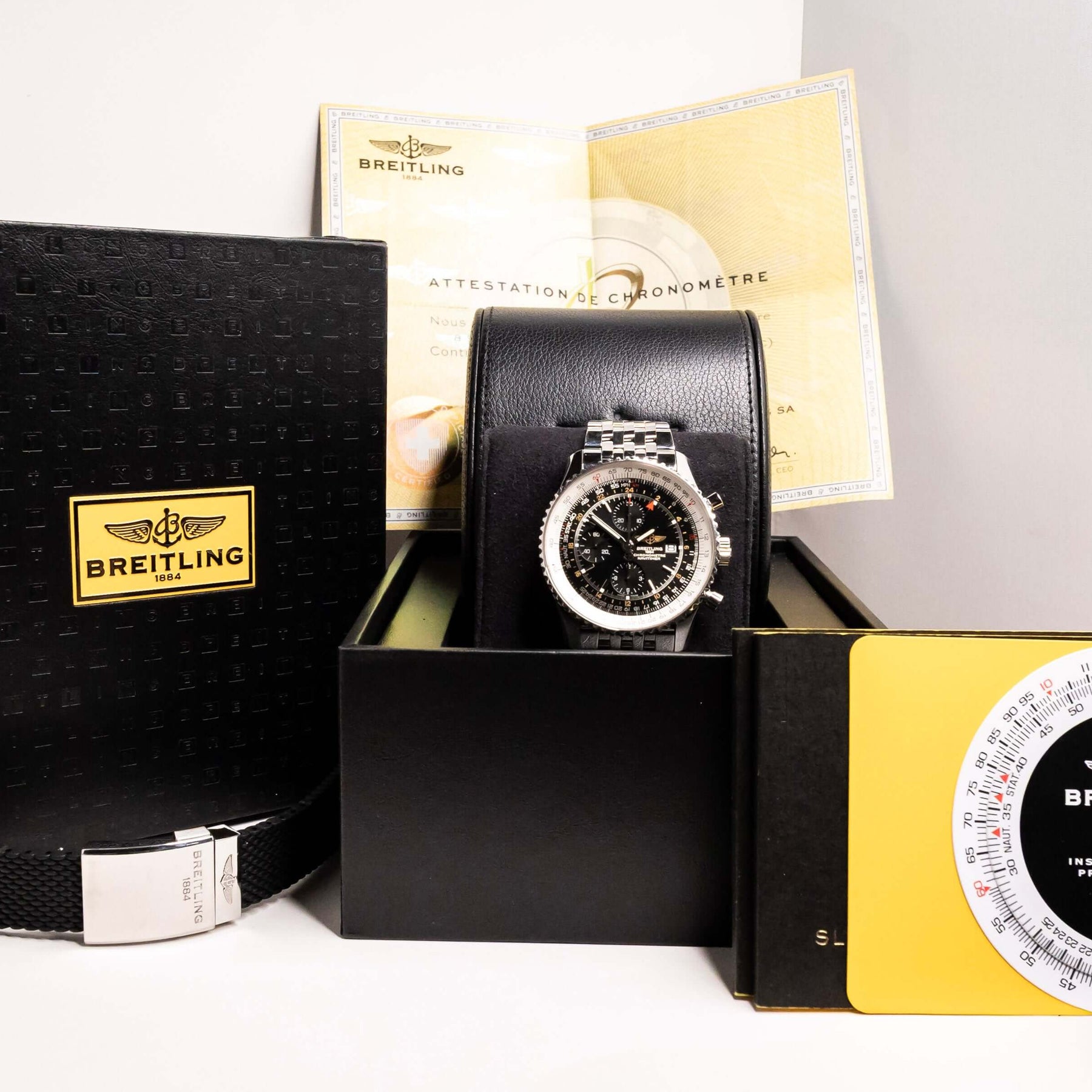 Breitling Navitimer World Chronograph displayed with its box, certification papers, and slide rule calculator.