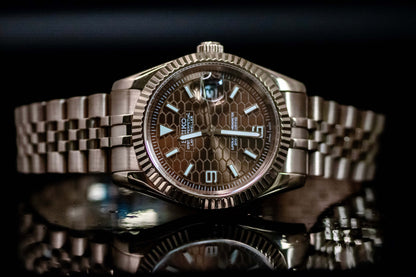 Seiko Mod Rose Gold Land Dweller watch with chocolate dial and rose gold case on a reflective surface.