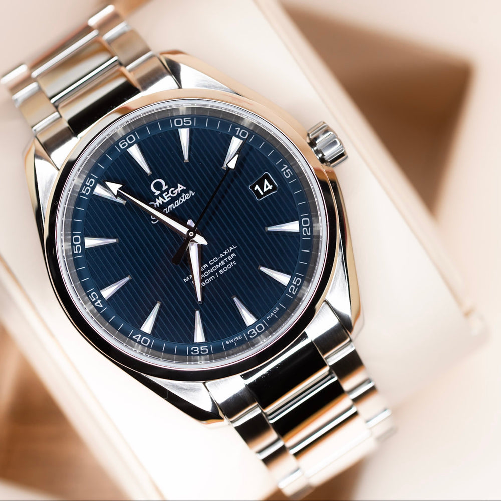 Omega Seamaster Aqua Terra 150M complete set displayed on a watch pillow with a blue dial.