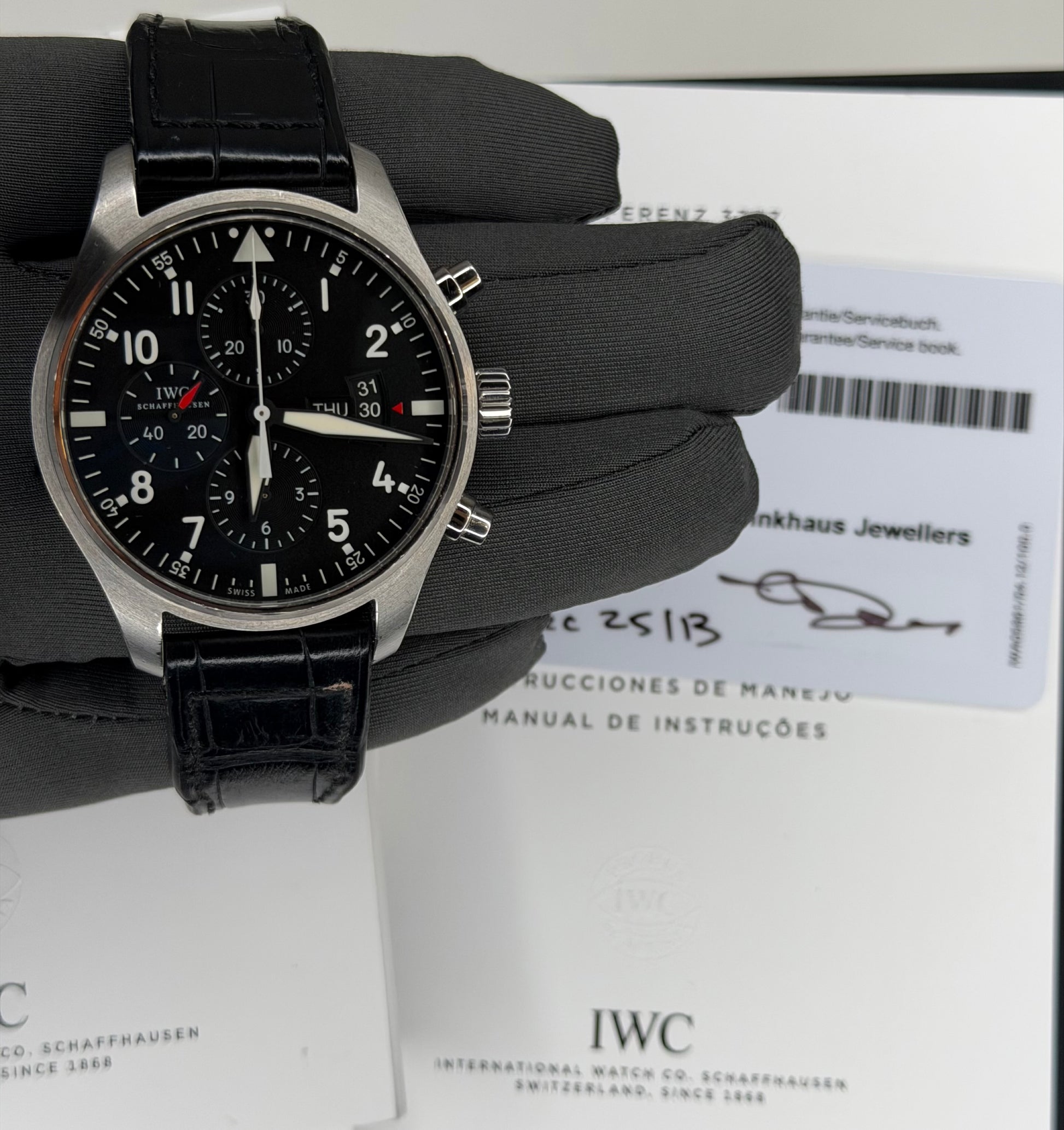IWC Pilots Watch Chronograph displayed with original box and papers on a gray glove background