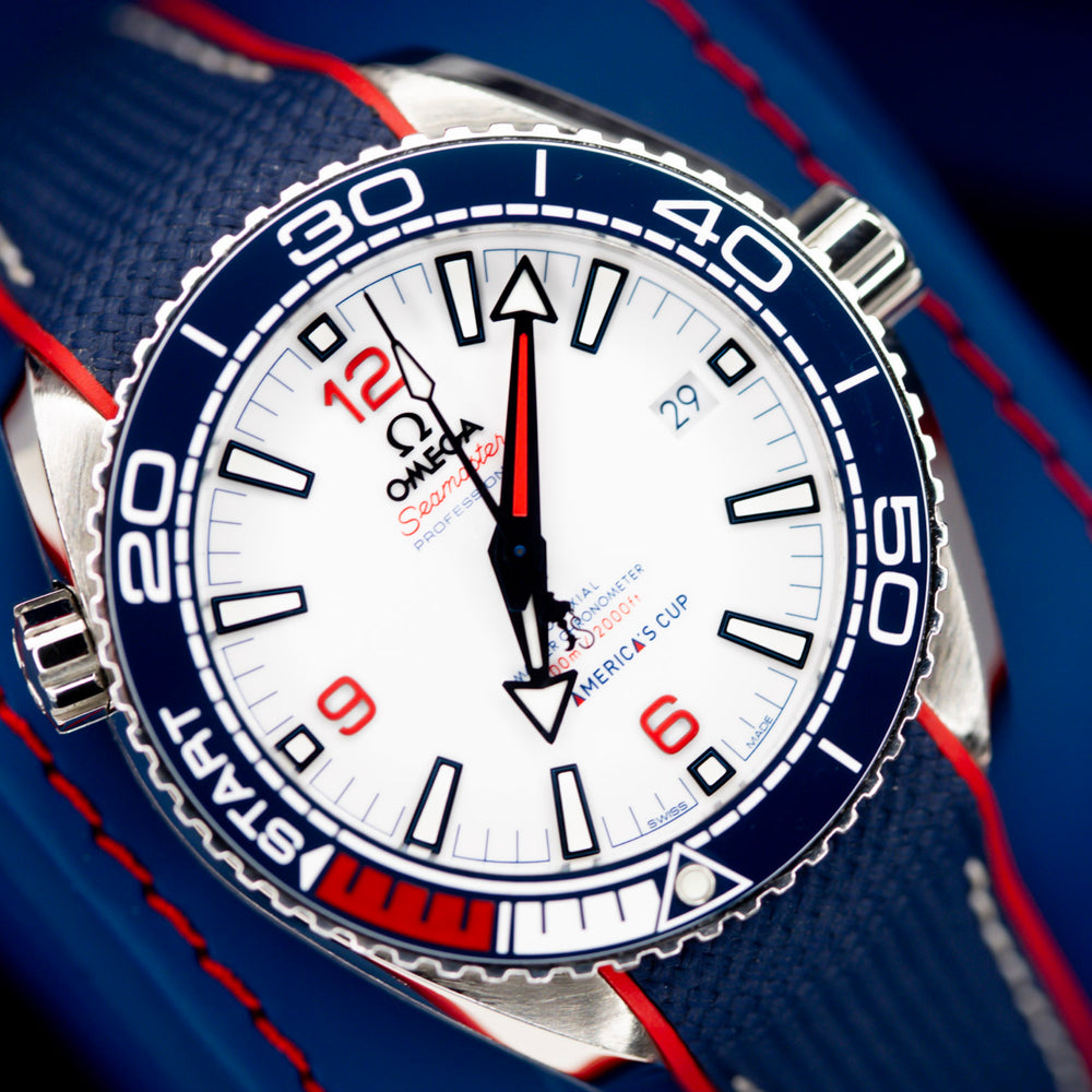Omega Seamaster America's Cup watch close-up with white dial and blue accents.