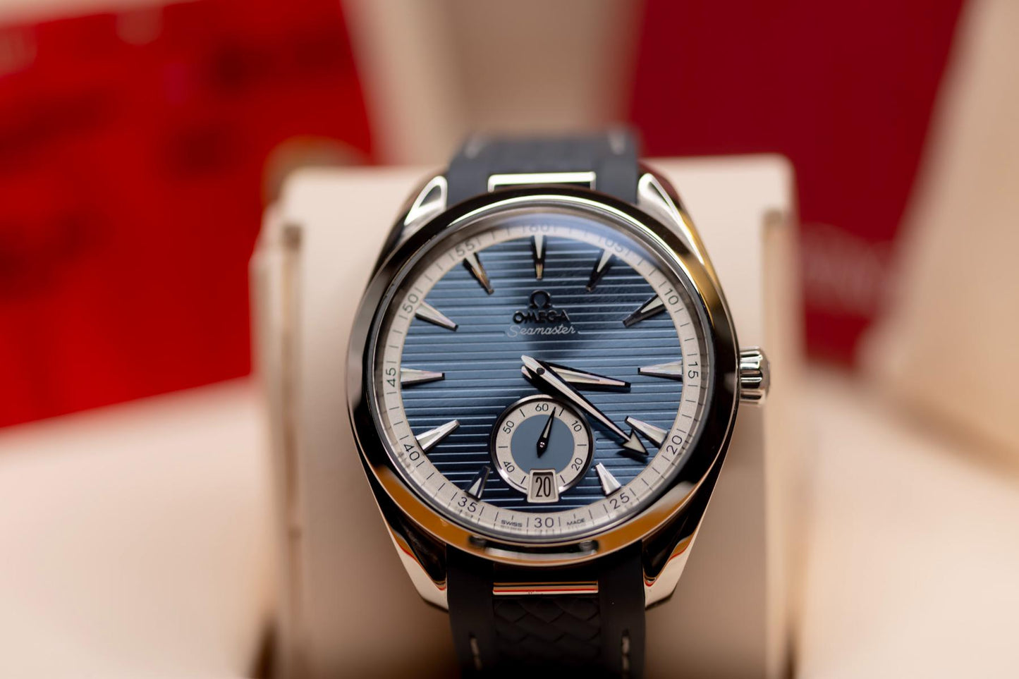 Omega Seamaster Aqua Terra 150M blue dial displayed on a stand with blue rubber strap and small seconds subdial.