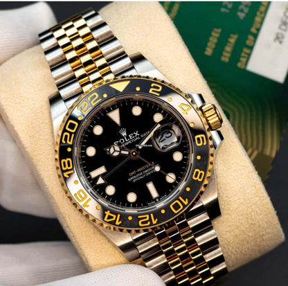 2024 Rolex GMT-Master II GRNR displayed on a soft cushion, featuring a black dial and two-tone Oystersteel and gold bracelet.