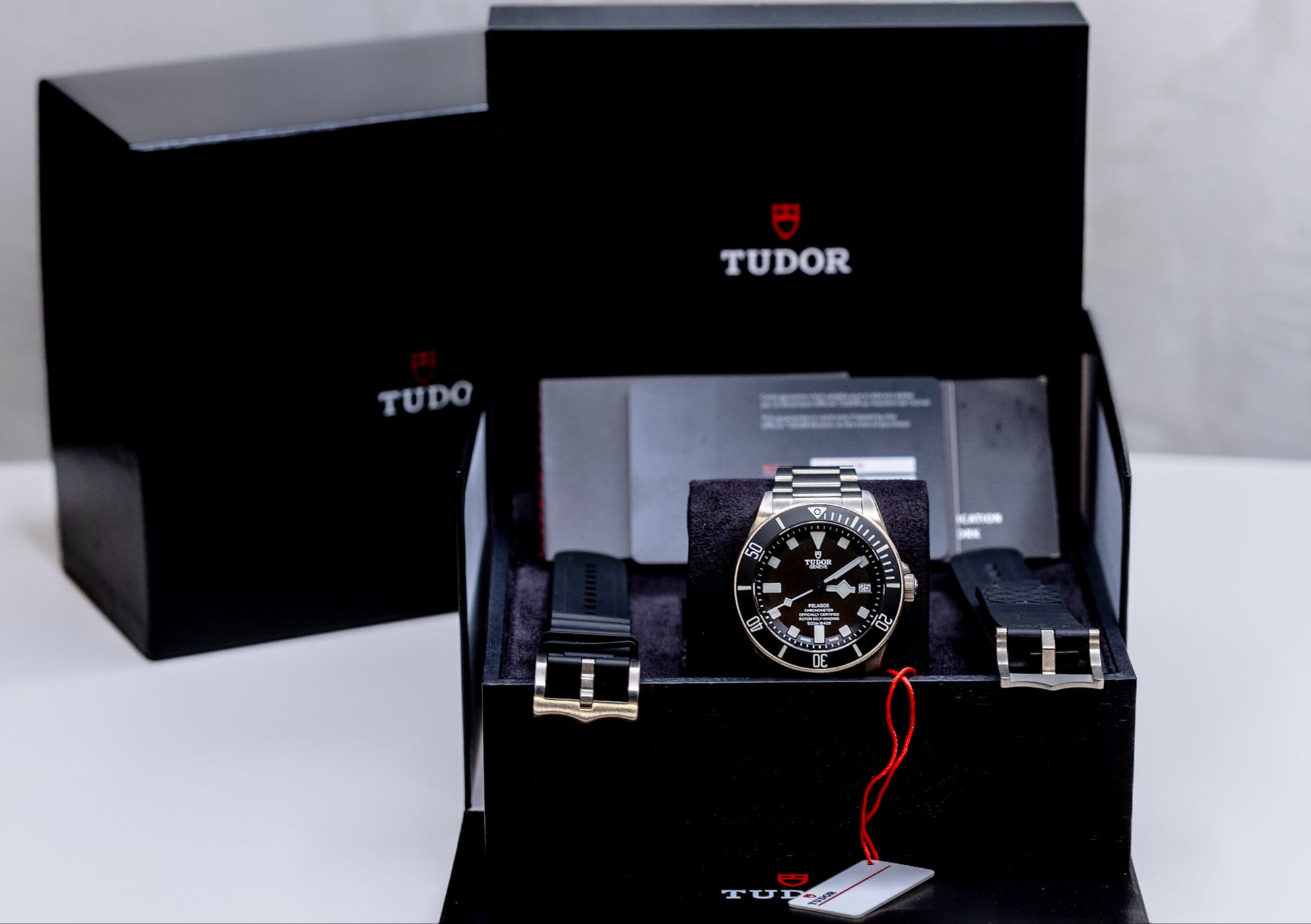 Tudor Pelagos dive watch displayed in luxury packaging with extra straps and certification details.