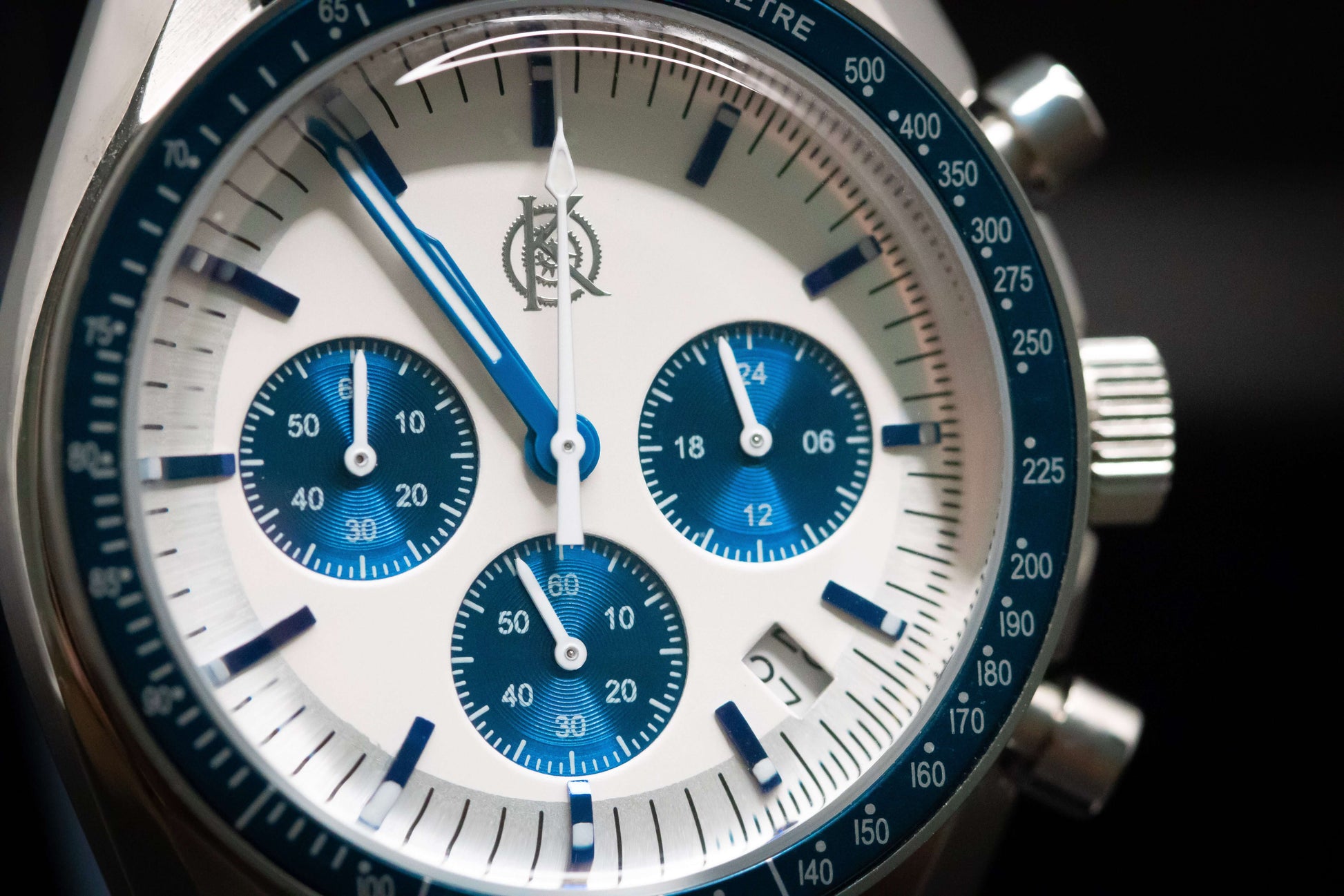 Close-up of KWC Snoopy Chronograph watch featuring a white dial and blue accents on a stainless steel case.