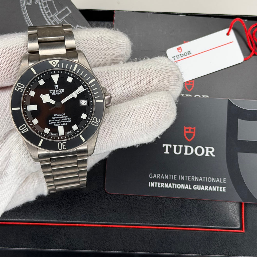 Tudor Pelagos dive watch displayed with a titanium case and bracelet, featuring a black dial and international guarantee card.