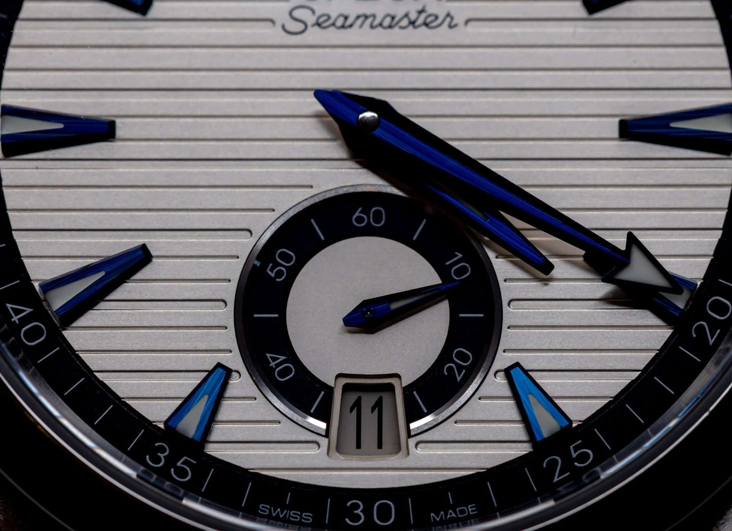 Close-up of the Omega Aqua Terra Small Seconds watch dial showcasing its unique silver teak-pattern and blue hands.