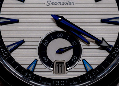 Close-up of the Omega Aqua Terra Small Seconds watch dial showcasing its unique silver teak-pattern and blue hands.
