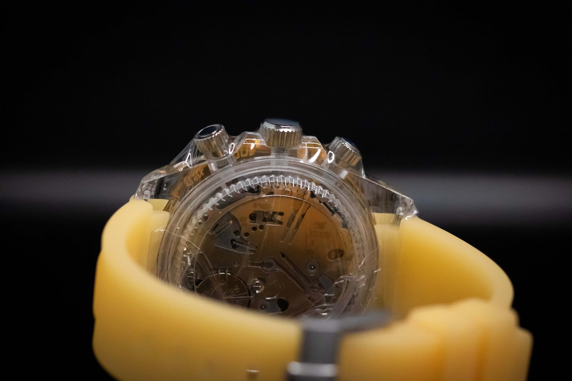 Back view of KWC Orange Ceramic Chronograph with a transparent case and yellow strap showcasing intricate mechanics.