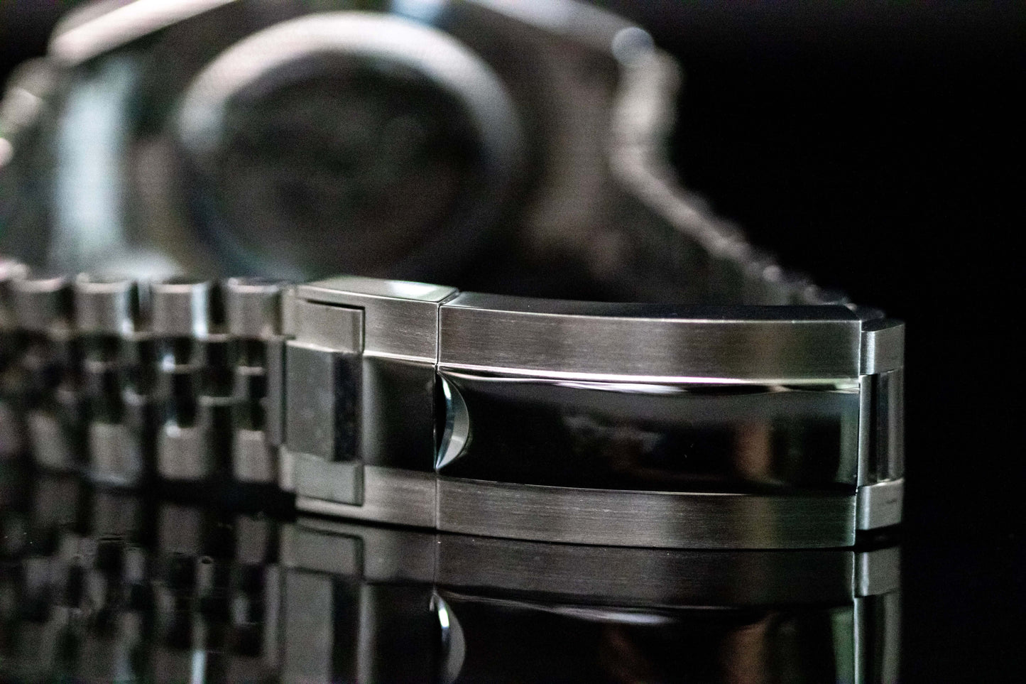 Close-up of the polished stainless steel bracelet clasp of the Ice Blue Seiko Mod Land Dweller watch on a reflective surface.