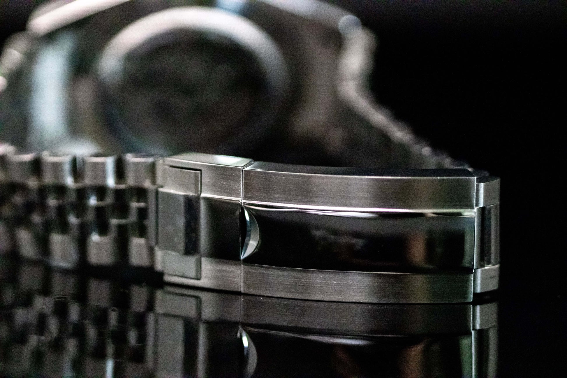 Close-up of the polished stainless steel bracelet clasp of the Ice Blue Seiko Mod Land Dweller watch on a reflective surface.