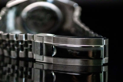 Close-up of the polished stainless steel bracelet clasp of the Ice Blue Seiko Mod Land Dweller watch on a reflective surface.