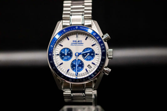 Seiko Speedmaster Snoopy watch with white dial, blue accents, stainless steel case, and bracelet.