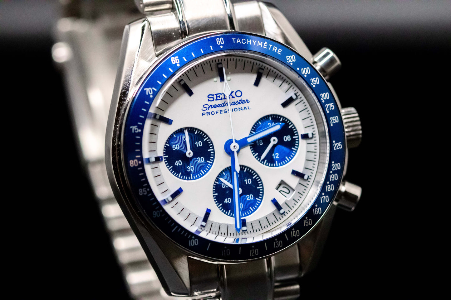 Seiko Speedmaster Snoopy watch with white dial, blue accents, and stainless steel bracelet, showcasing precision and style.