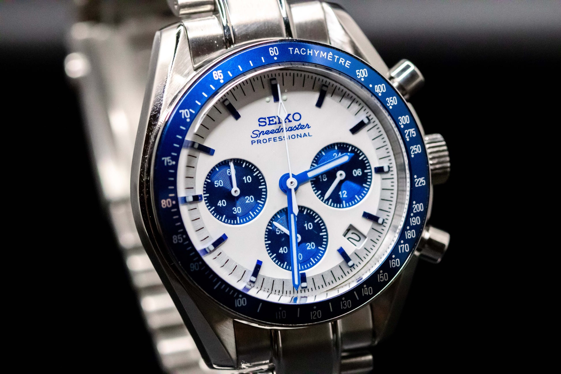 Seiko Speedmaster Snoopy watch with white dial, blue accents, and stainless steel bracelet, showcasing precision and style.