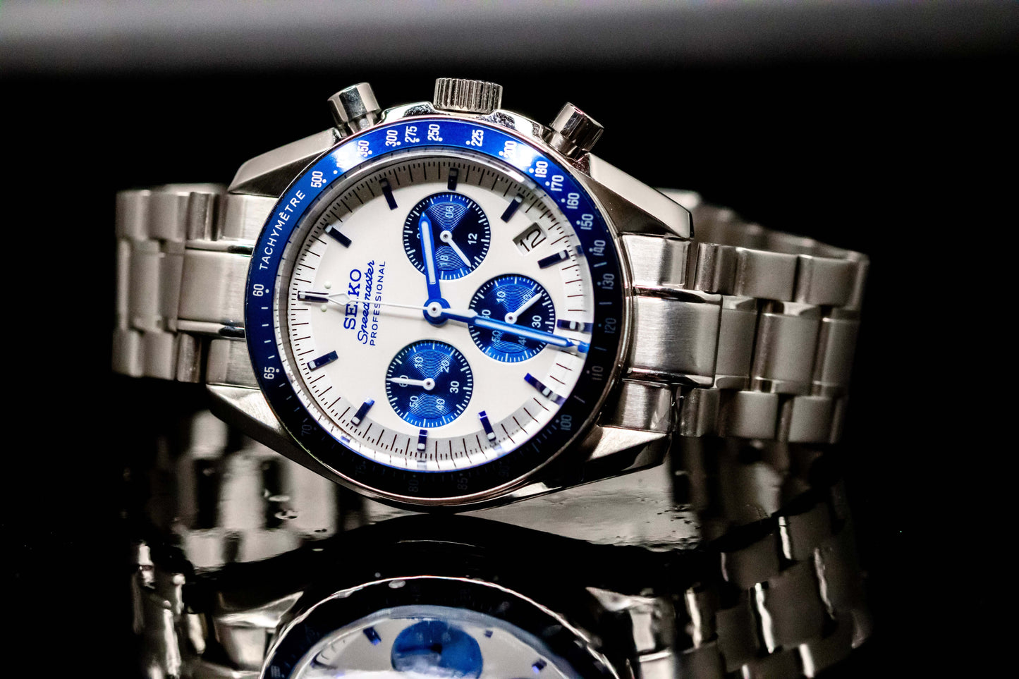 Seiko Speedmaster Snoopy watch with a white dial and blue accents on a stainless steel bracelet, showcasing precision craftsmanship.