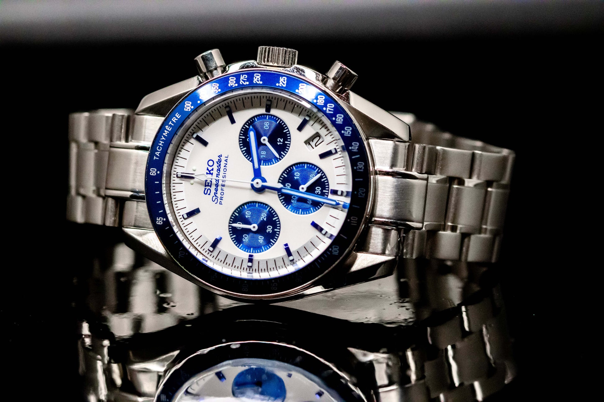 Seiko Speedmaster Snoopy watch with a white dial and blue accents on a stainless steel bracelet, showcasing precision craftsmanship.