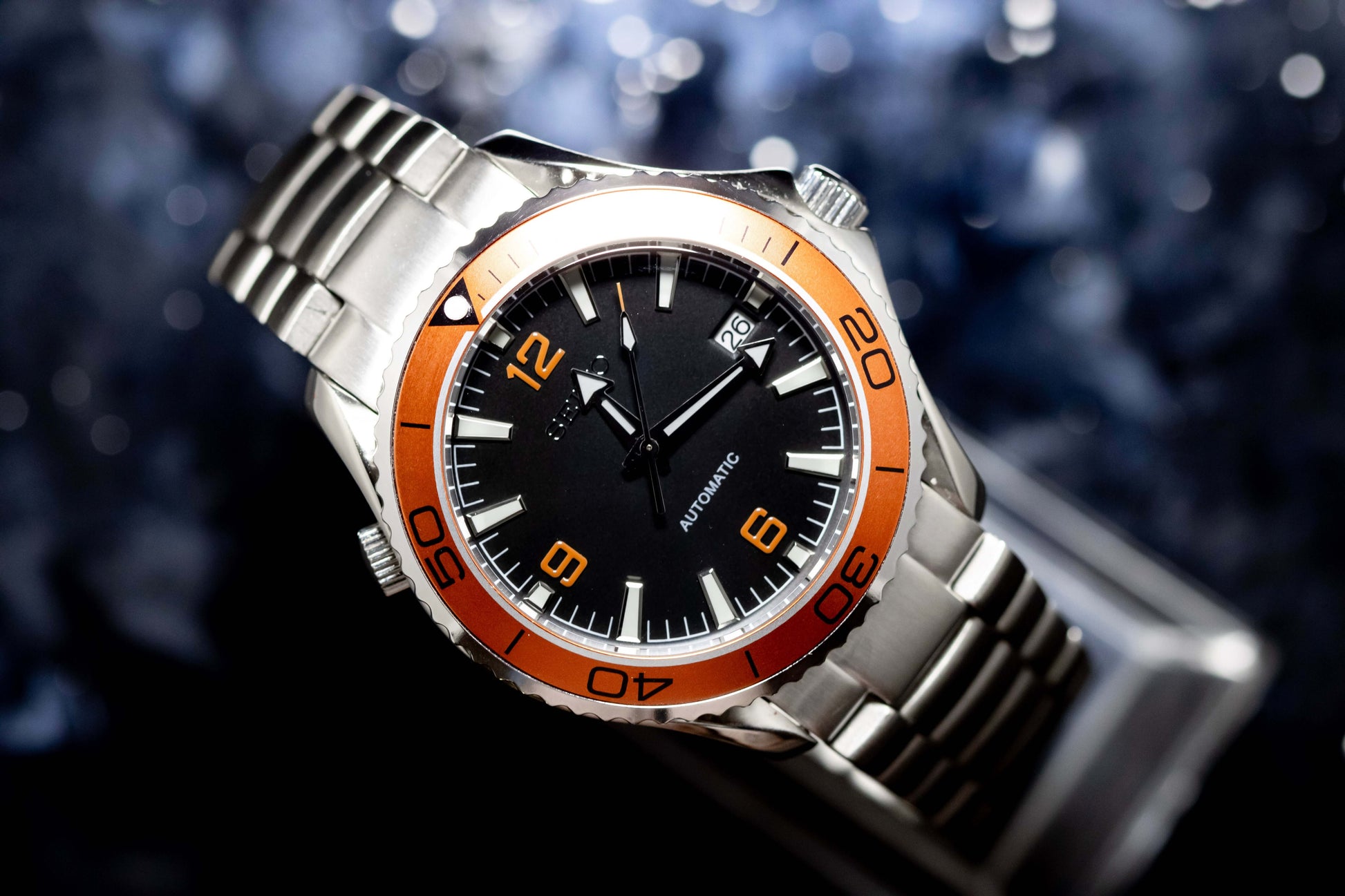Seikomod Tiger Seamaster watch featuring a black dial, orange numerals, and stainless steel frame, ideal for style and precision.