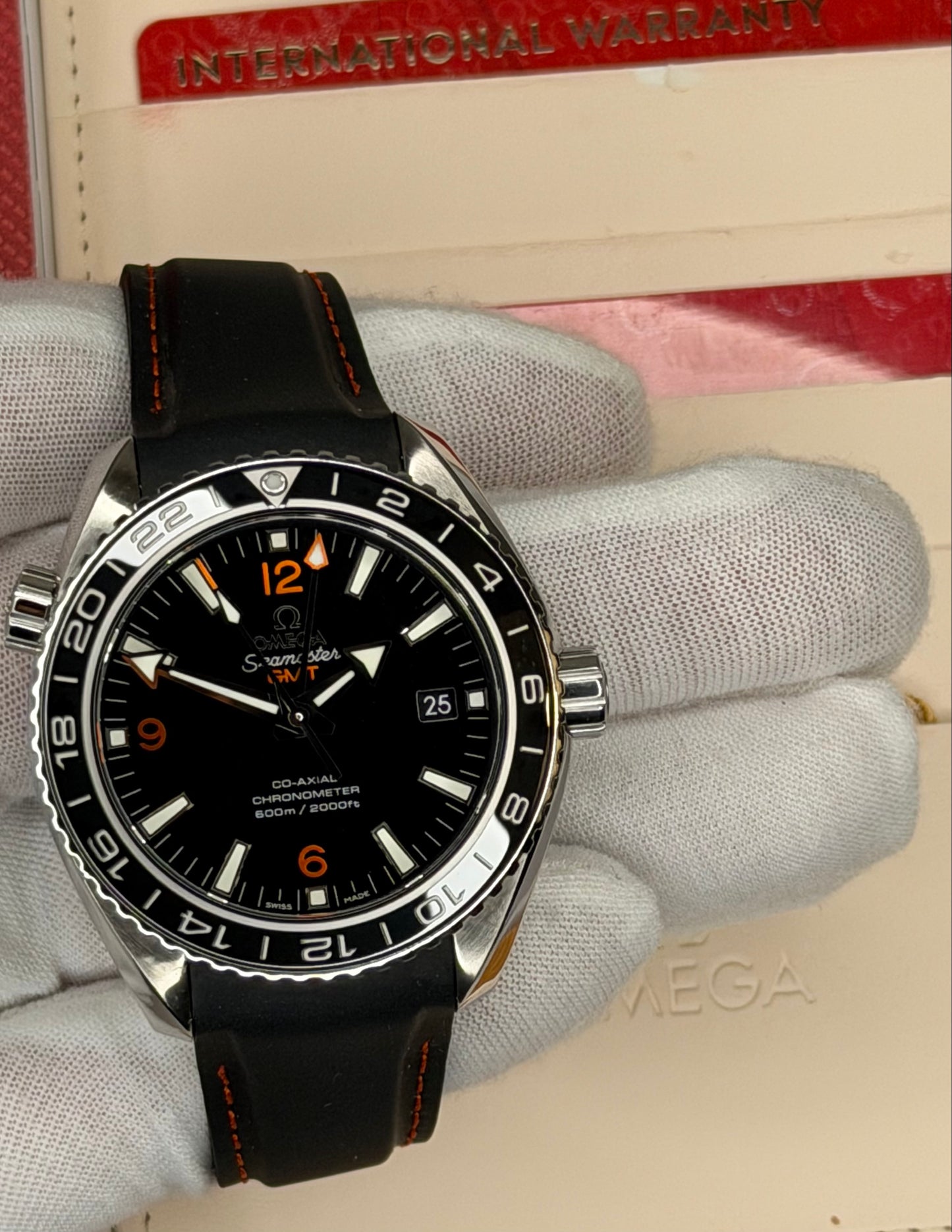 2024 Omega Seamaster Planet Ocean GMT watch displayed with original warranty box.