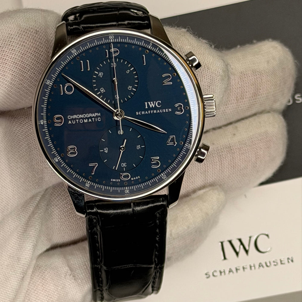 Unworn IWC Portuguese chronograph displayed with a blue dial and black leather strap in pristine condition.