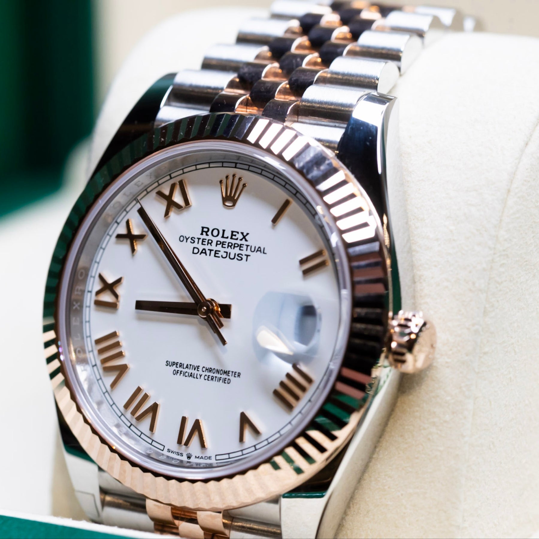 2025 Rolex Datejust 41 rose gold watch displayed in a luxurious watch box with a white dial and Roman numerals.
