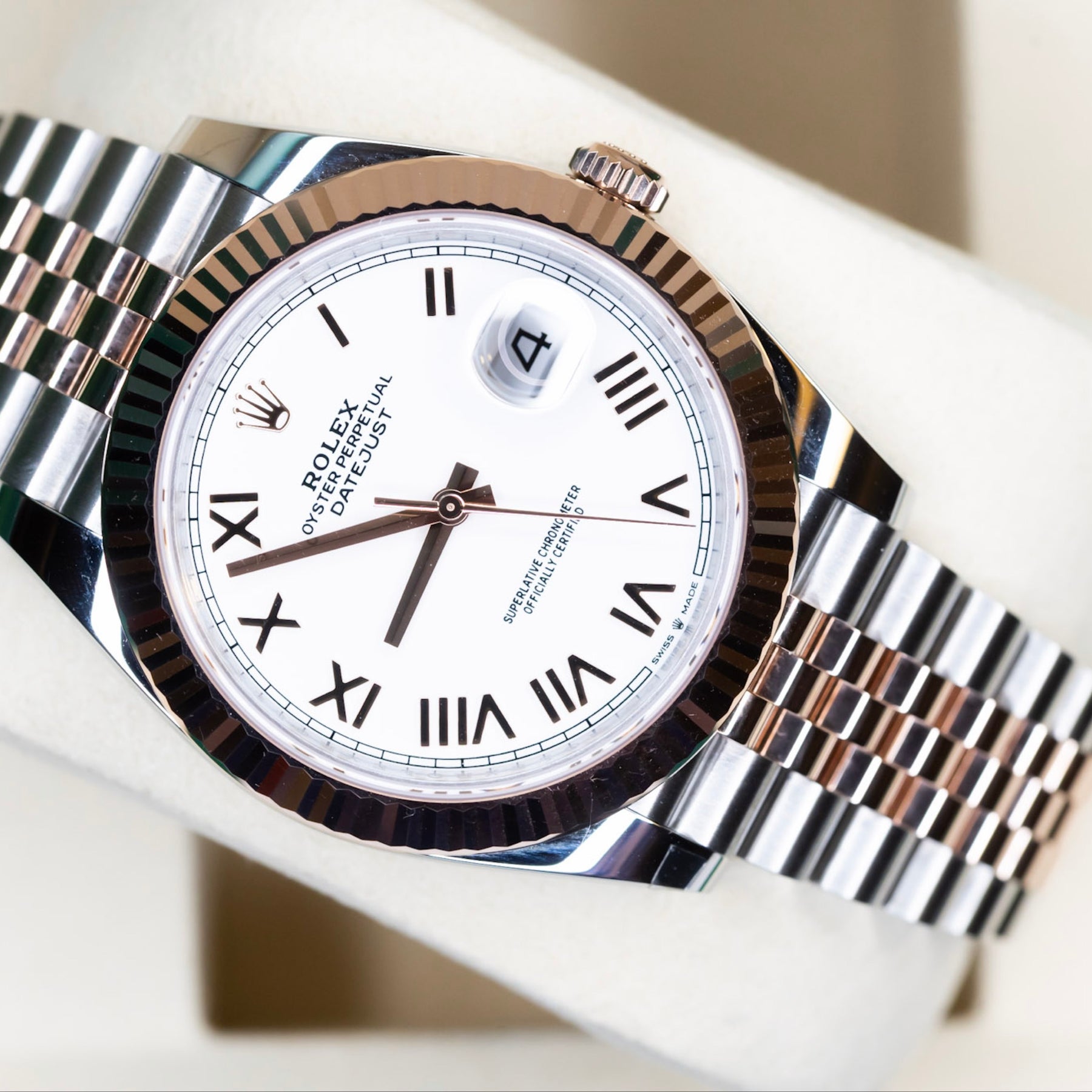 2025 Rolex Datejust 41 rose gold watch displayed on a soft cushion, featuring a two-tone bracelet and white dial.