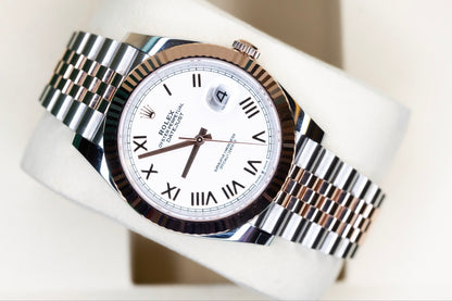 2025 Rolex Datejust 41 rose gold watch displayed on a soft cushion, featuring a two-tone bracelet and white dial.