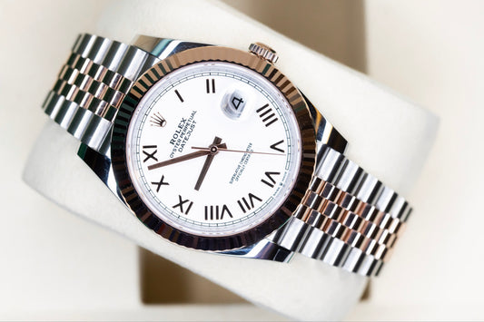 2025 Rolex Datejust 41 rose gold watch displayed on a soft cushion, featuring a two-tone bracelet and white dial.