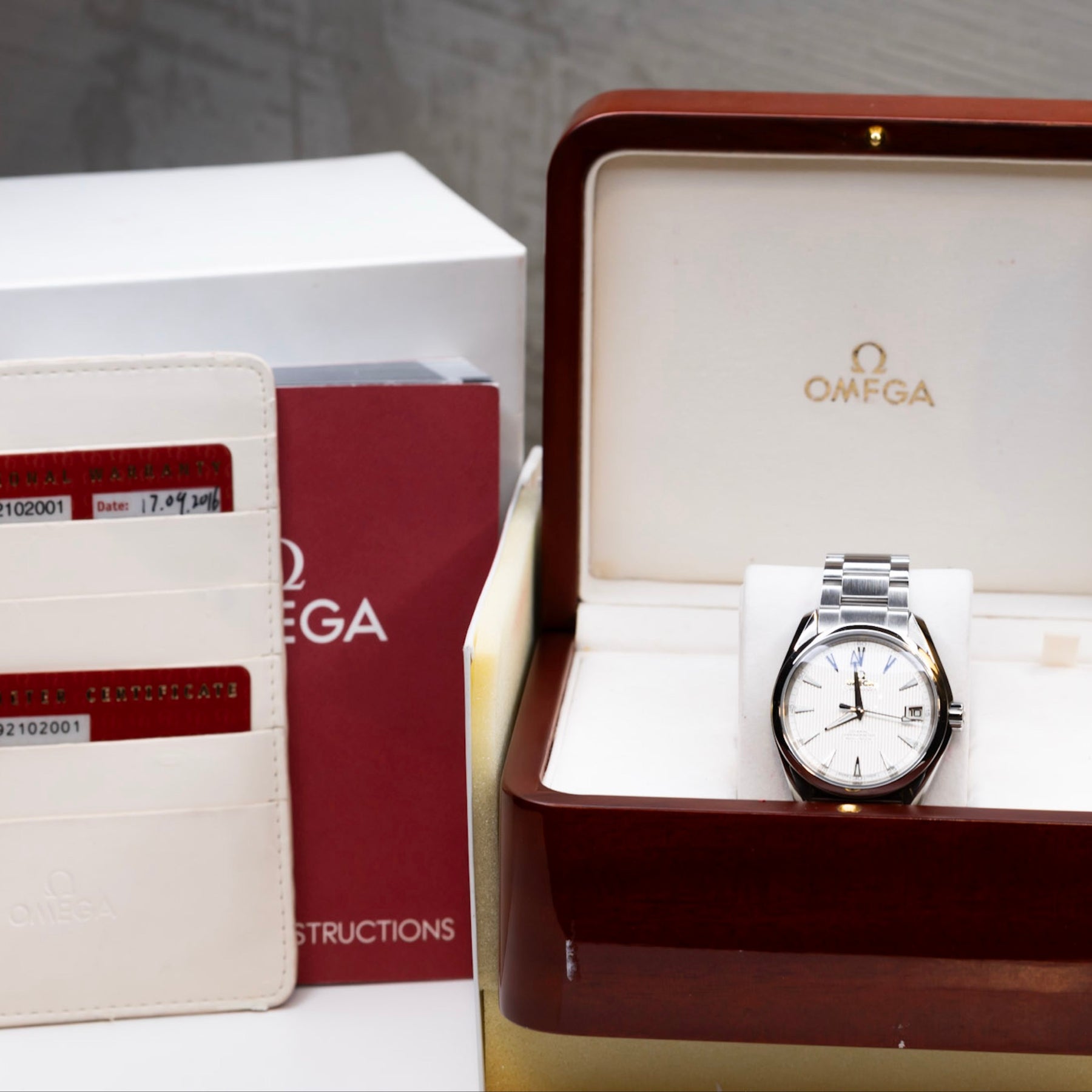 2016 Omega Seamaster Aqua Terra watch displayed in its original box with papers, featuring a white lacquered dial.