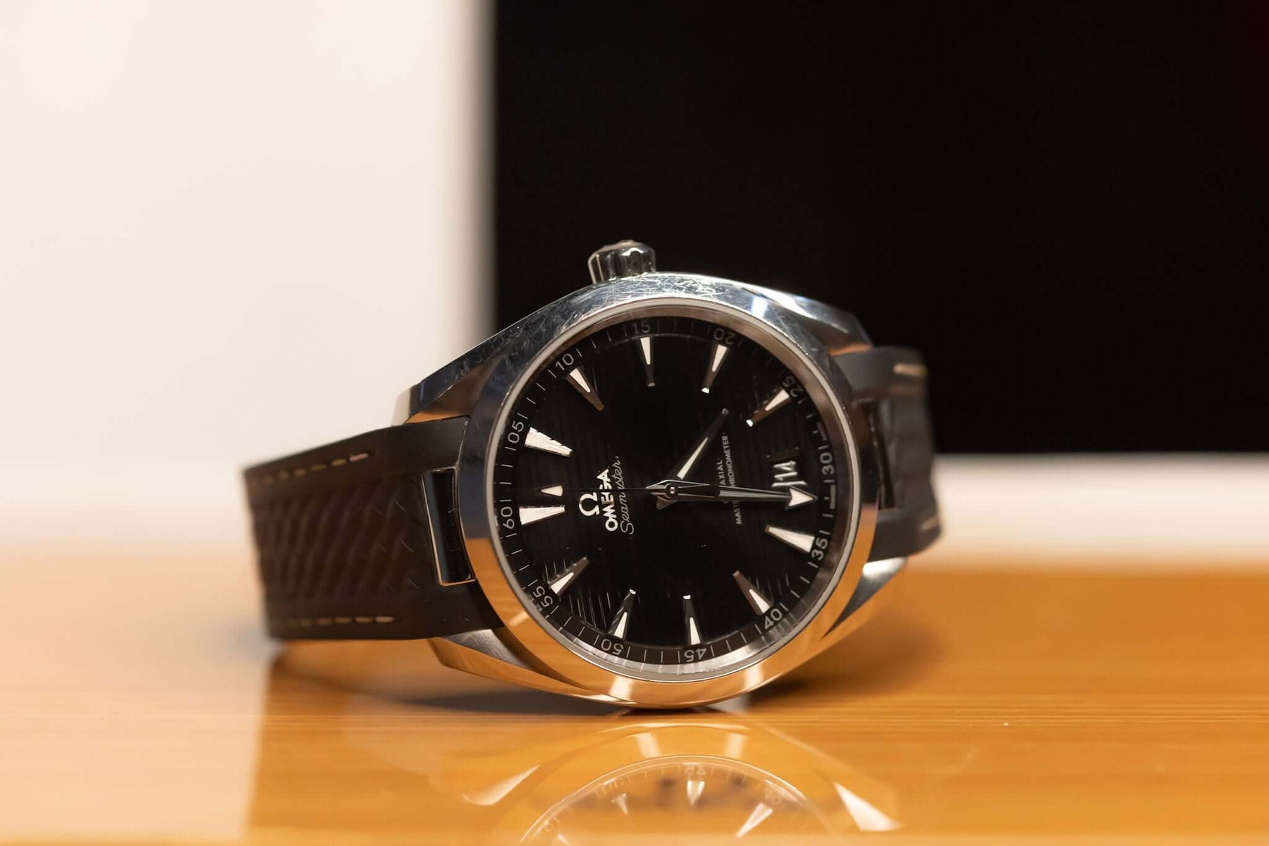 2022 Omega Seamaster Aqua Terra watch with black dial and stainless steel case on a wooden surface.