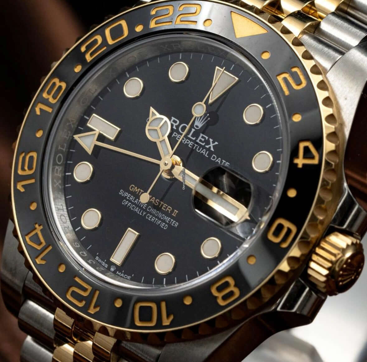 2024 Rolex GMT-Master II GRNR close-up showing black and gold dial with Oystersteel and 18K yellow gold details.