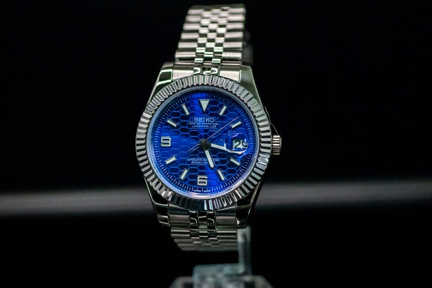 Blue SeikoMod Land Dweller watch on display with a stainless steel bracelet and bold blue dial.