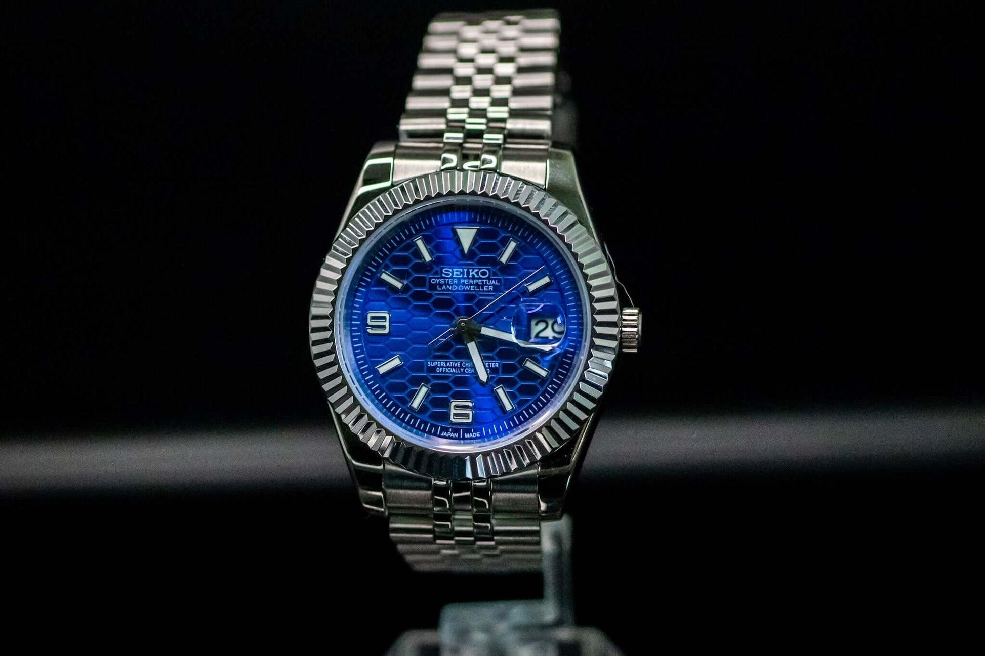 Blue SeikoMod Land Dweller watch on display with a stainless steel bracelet and bold blue dial.