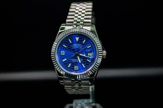 Blue SeikoMod Land Dweller watch on display with a stainless steel bracelet and bold blue dial.