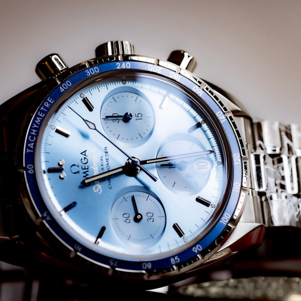 Omega Speedmaster 38mm blue dial chronograph with polished stainless steel bracelet and blue tachymetric bezel.