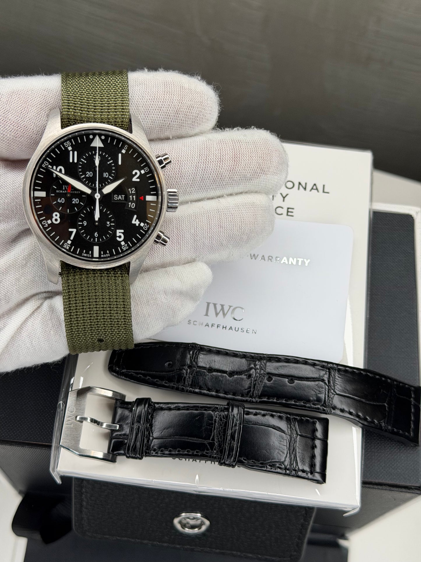IWC Pilot's Watch Chronograph 43mm with green strap and black dial, includes warranty card and additional leather strap.