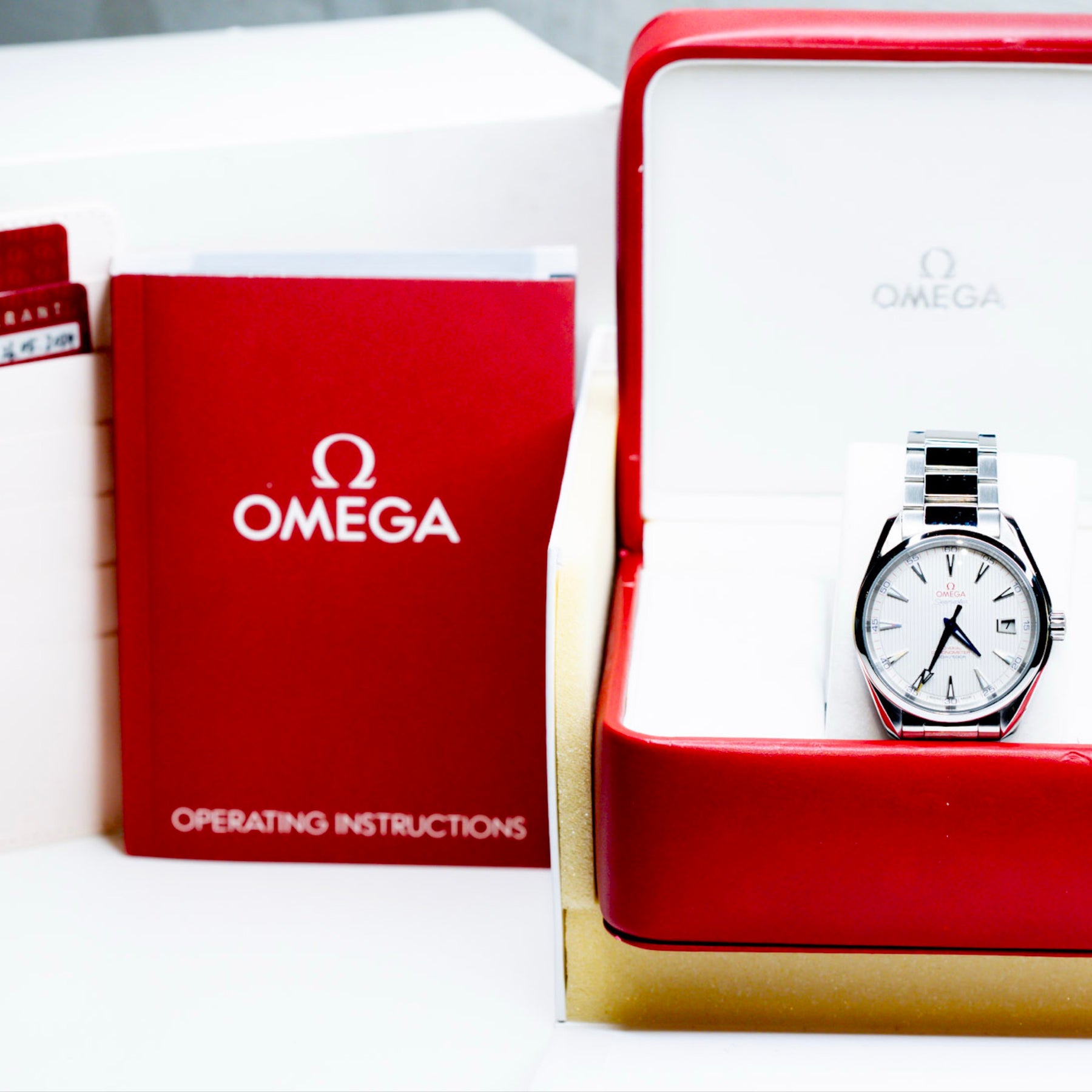 2018 Omega Seamaster Aqua Terra watch in original box with papers, showcasing bright opaline dial and red accents.
