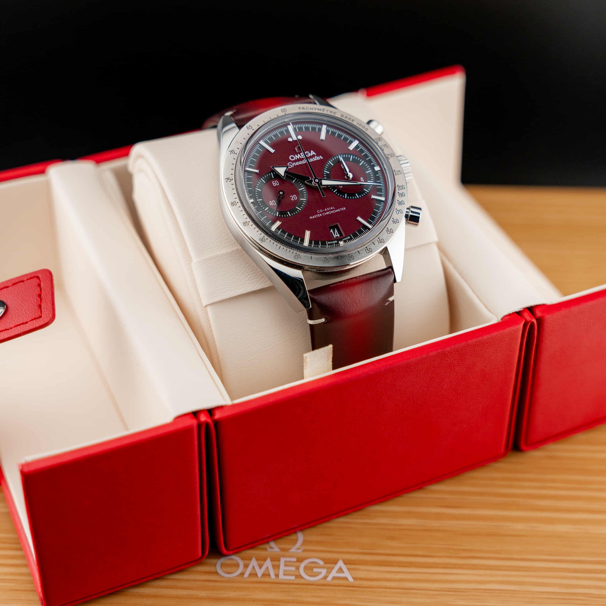 Omega Speedmaster '57 Burgundy full set displayed in a luxury box with deep burgundy dial and stainless steel case.