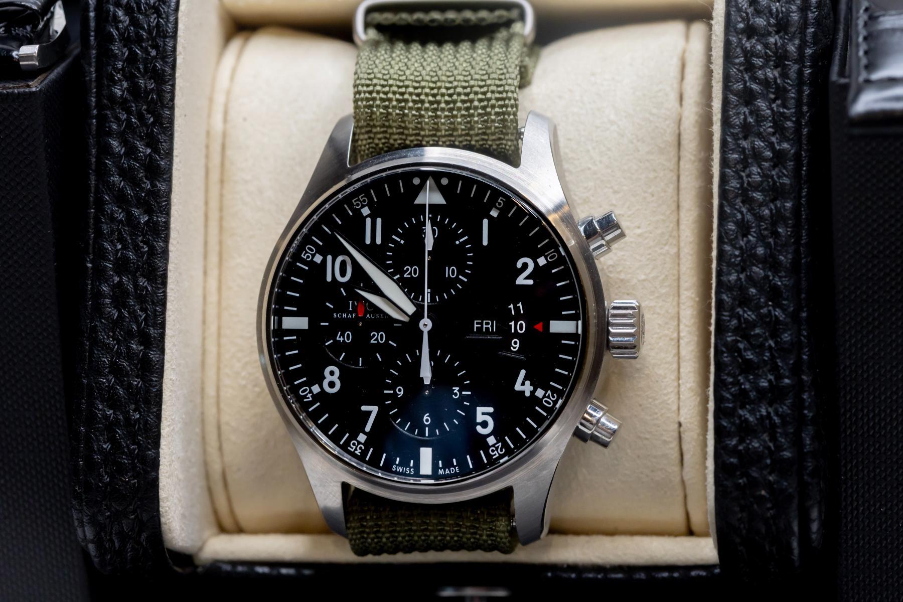 IWC Pilot's Watch Chronograph 43mm displayed in a watch box with a black dial and green strap.