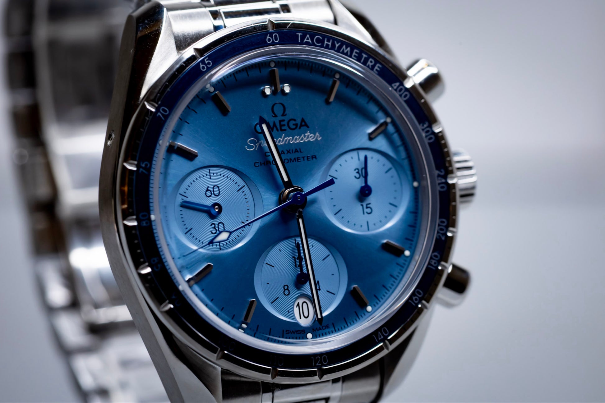 Omega Speedmaster 38mm blue dial chronograph with polished/satin dual bezel and subdials.