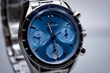 Omega Speedmaster 38mm blue dial chronograph with polished/satin dual bezel and subdials.