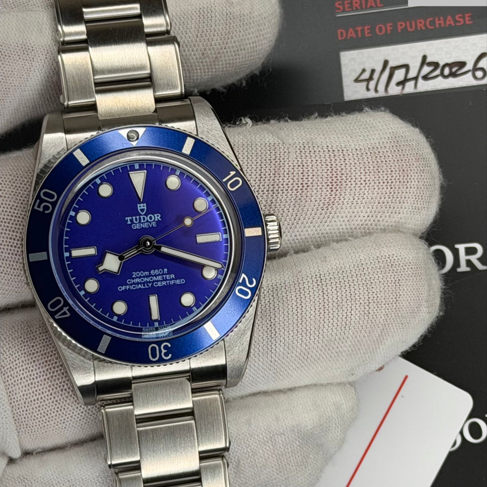 2026 Tudor Black Bay watch showcased with a blue dial, featuring original box and papers, and steel bracelet.